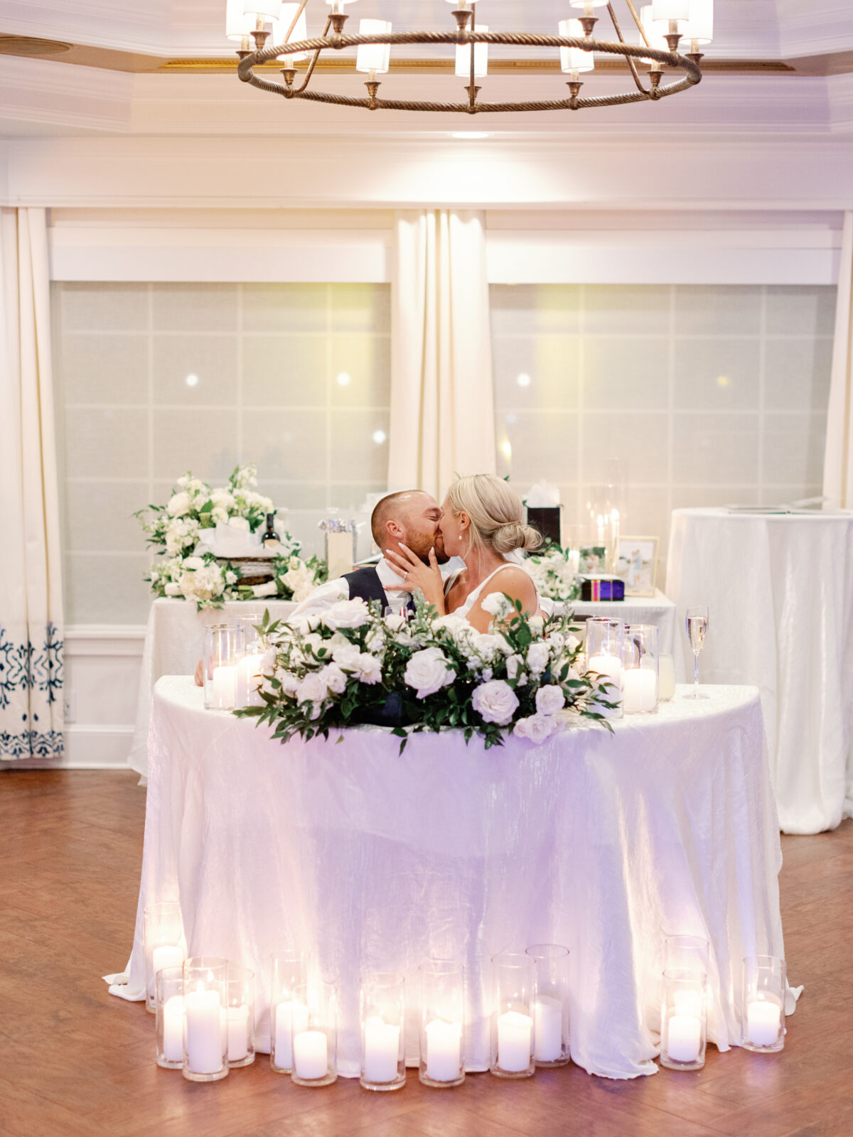 couple kisses at their sweetheart table with candles all around 