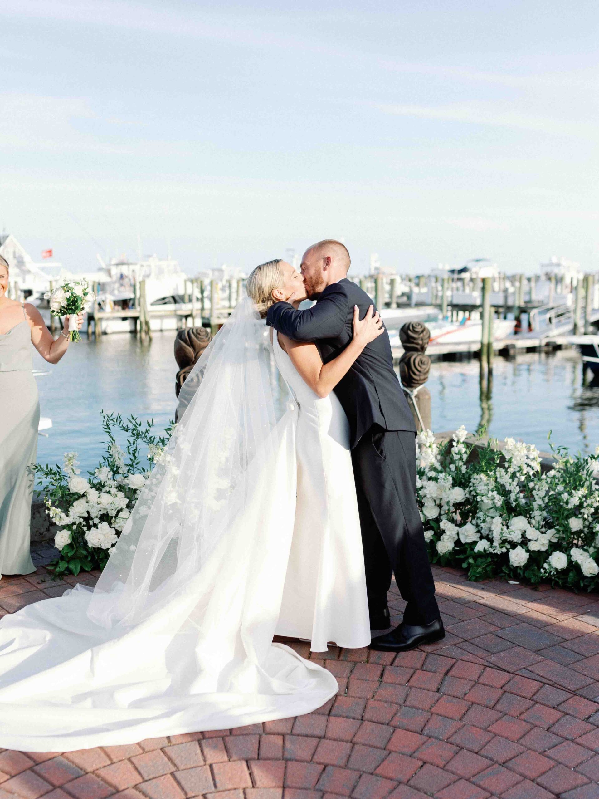 bride and groom share their first kiss with the marina in the background 