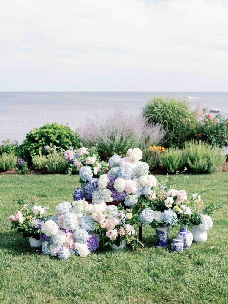 multicolored hydrangeas in blue vases set in front of a garden overlooking Long Island Sound