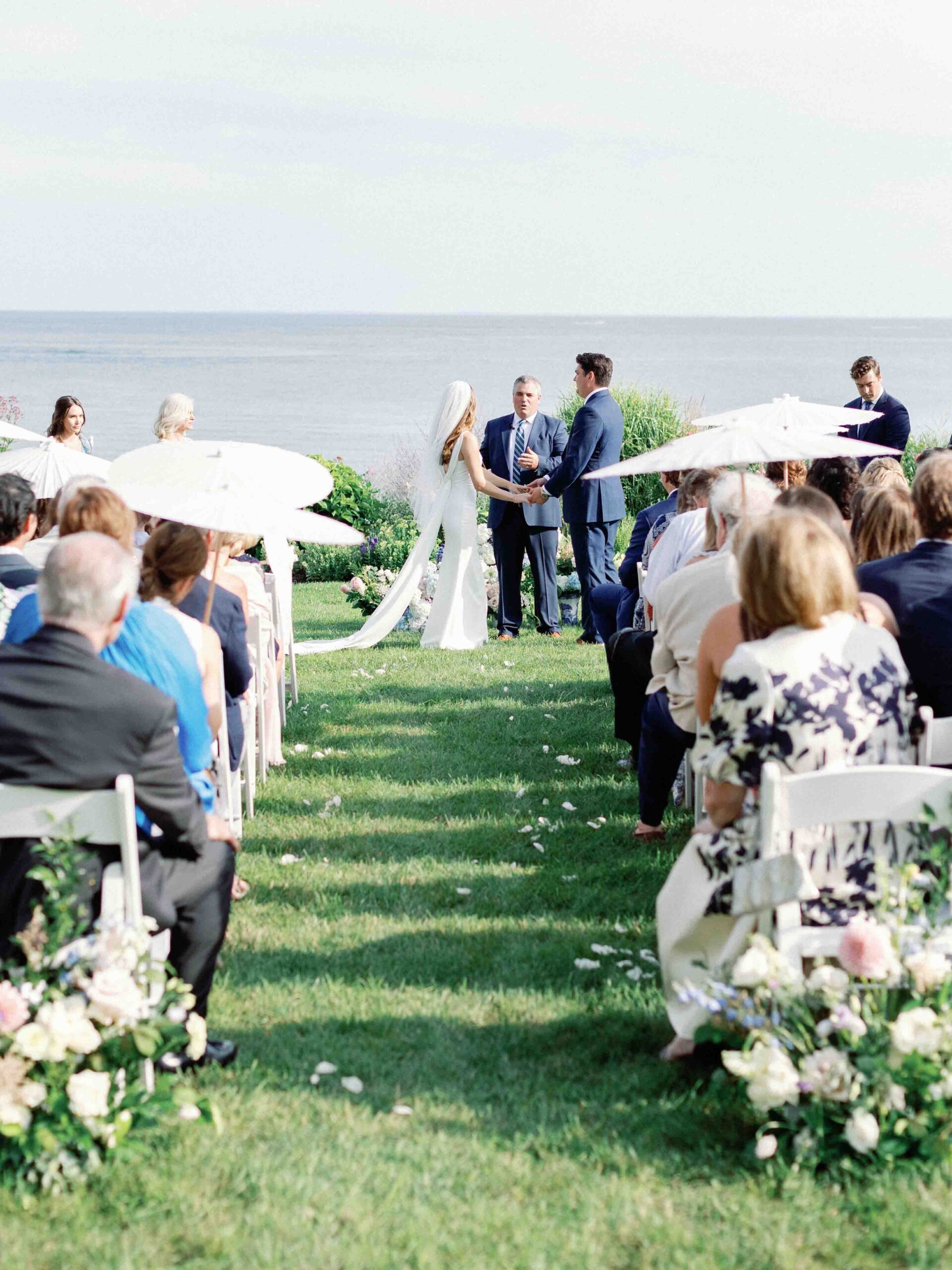 bride and groom holding hands at tje front of the aisle. Long island sound is in the background
