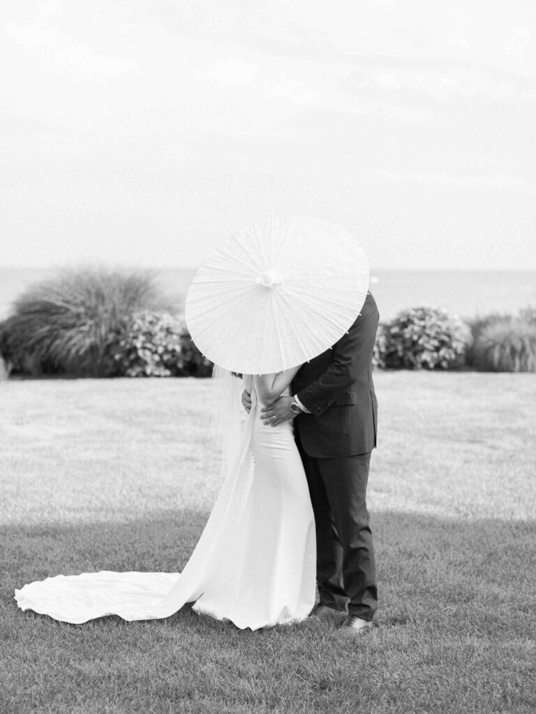 bride and groom hiding behind a parasol  
