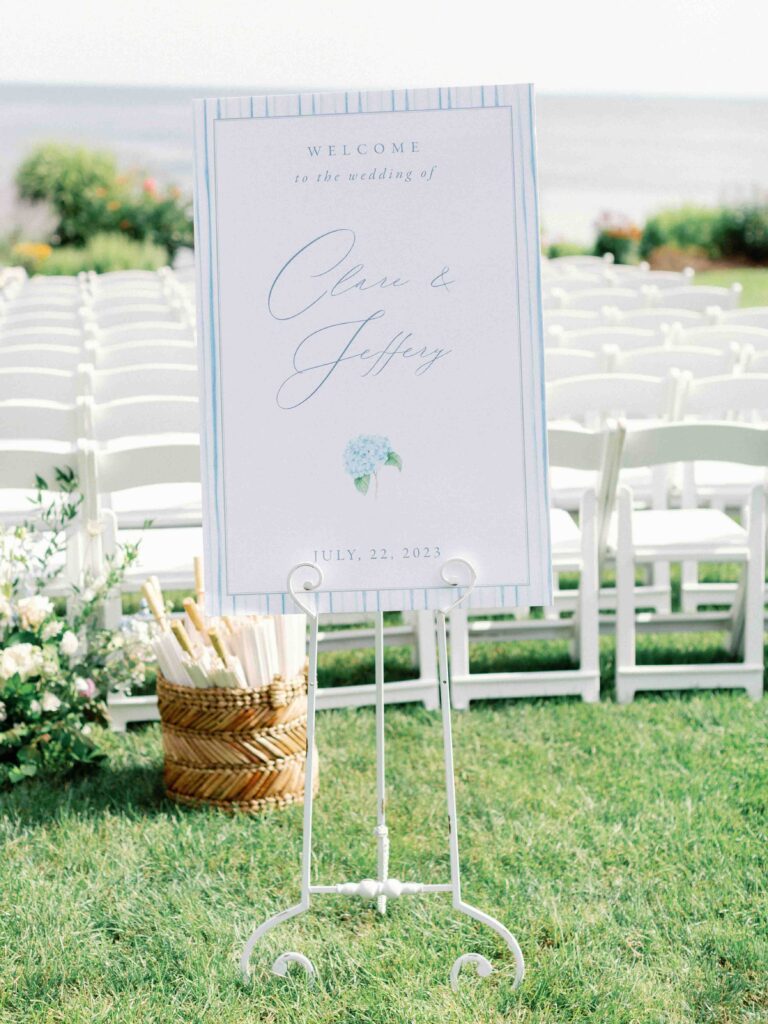 wedding ceremony welcome sign with light blue calligraphy stating the couples names